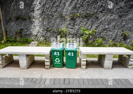 Eine leere Parkbank neben einem grünen Mülleimer Stockfoto