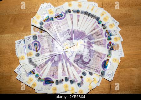 Ein kreisförmiges Arrangement britischer 20-Pfund-Banknoten, verteilt auf einem Holztisch. Die Noten sind aufgefächert und zeigen ihre violette Farbe und Farbe Stockfoto