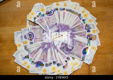 Ein kreisförmiges Arrangement britischer 20-Pfund-Noten auf einer hölzernen Oberfläche. Die Noten sind aufgefächert und zeigen ihre violette Farbe und ihre Komplexität Stockfoto