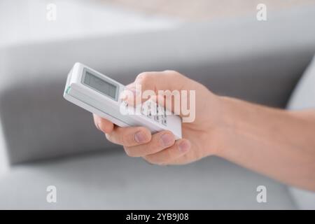 Männliche Hand mit Fernbedienung der Klimaanlage, Nahaufnahme Stockfoto