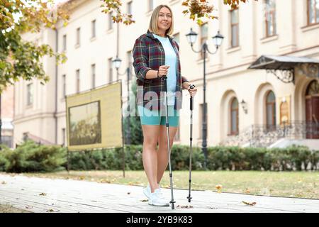 Sportliche Frau beim Nordic Walking auf der Straße Stockfoto