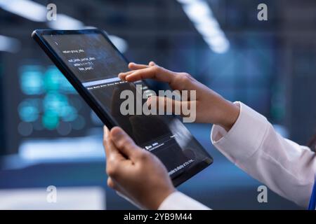Der Techniker überprüft den Wiederherstellungsplan auf einem Tablet und überwacht den Energieverbrauch des Rechenzentrums. Mitarbeiter im Serverraum, der sicherstellt, dass die Sensoren optimal funktionieren, routinemäßige Datenträgerprüfungen durchführt, Nahaufnahme Stockfoto