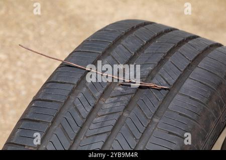 Reifenpannen am Fahrzeug durch Metalldraht. Fahrzeugsicherheit, Reifenpannen, Reifenwartung, Reparatur und Luftdruckkonzept Stockfoto