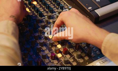 Audiotechniker dreht die Vorverstärker-Regler und -Tasten auf der Schalttafel im Kontrollraum und verwendet die Bearbeitungskonsole zum Mischen und Mastering von Titeln. Professioneller Ortungsingenieur im Musikstudio. Kamera A.. Stockfoto