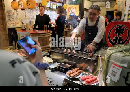 Ein Koch, der Yakiniku eine japanische Art von gegrilltem Fleisch für einen Izakaya im Nishiki Market aka Kyoto's Kitchen in der Innenstadt von Kyoto, Japan, zubereitet Stockfoto