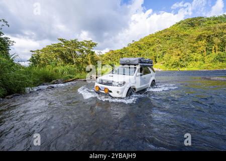 Toyota Geländewagen mit Dachzelt fährt durch einen breiten Fluss im Regenwald, Provinz Alajuela, Costa Rica, Mittelamerika Stockfoto