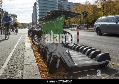 Verkehr, Mobilität, Radfahrer und aufgereihte E-Scooter aus Lime im Herbst auf einer Straße in Berlin, Deutschland, Europa Stockfoto