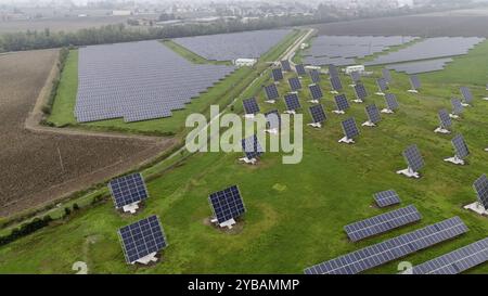 Eine Reihe von Sonnenkollektoren auf einem grünen Feld unter bedecktem Himmel Stockfoto