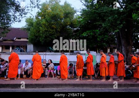 Mönche warten an der Schlange, um Reis von den Spendern während der Frühmorgendfeier auf der Sakkaline Road im historischen Viertel zu erhalten. Luang Prabang. Laos Stockfoto