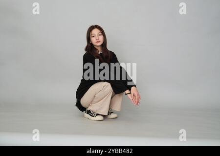 Ein 13-jähriges Mädchen, das in einem schicken Pullover wehmütig aussieht, verkörpert die leise Introspektion und Sensibilität, die in Teenagern üblich ist. Stockfoto