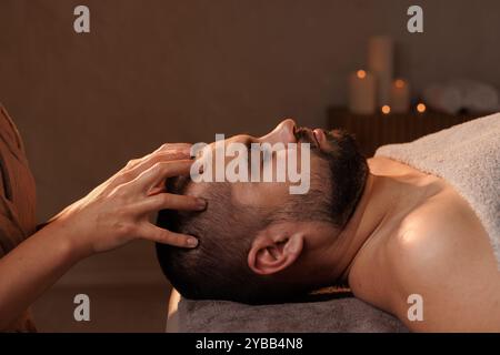 Junger Mann, der eine Gesichtsmassage im Schönheitssalon bekommt, Nahaufnahme Stockfoto
