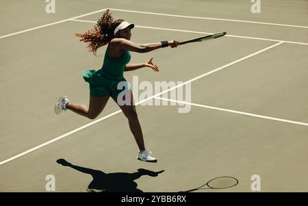 Professionelle Tennisspielerin, die während eines Spiels auf dem Platz einen mächtigen Vorhand-Treffer ausführt und Stärke und Geschick zeigt. Stockfoto