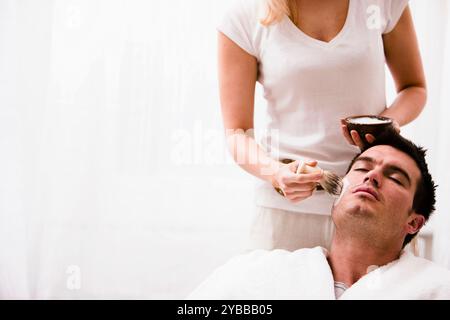 Anwendung von Rasierschaum auf Mann Gesicht Frau Stockfoto