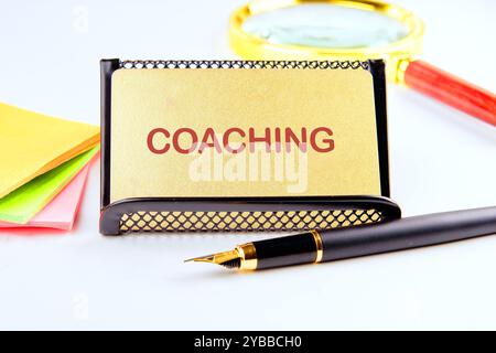 Geschäftskonzept. Der Satz, Text, Wortwahl COACHING ist auf einer goldenen Visitenkarte auf hellem Hintergrund geschrieben. Stockfoto