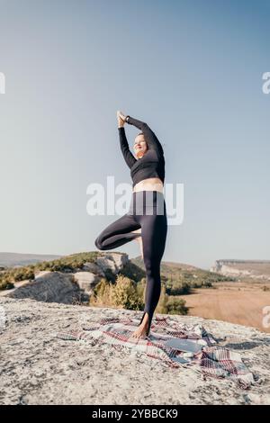 Frau, die Yoga auf dem Berggipfel praktiziert Stockfoto