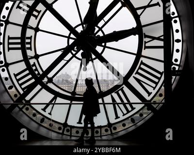 Eine menschliche Figur in Silhouette hebt sich von einer großen Uhr im Musée d'Orsay in Paris, Frankreich, ab Stockfoto