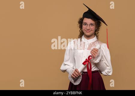 Teenager-Mädchen in Abschlussmütze mit Diplom und rotem Band. Absolvent feiert den Abschluss. Bildungskonzept. Erfolgreiche Grundschule. Stockfoto