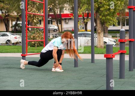 Frau im Ausfallschritt Stretch auf dem Spielplatz im Freien mit Schwerpunkt auf Bewegung und Flexibilität. Stockfoto