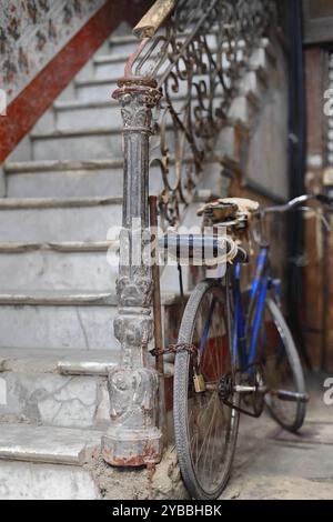 814 altes abgenutztes Fahrrad schlecht repariert, mit einem Vorhängeschloss an das schmiedeeiserne Geländer einer baufälligen weißen Marmortreppe, Haus in Habana Vieja. Havanna-Kuba Stockfoto
