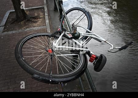 Ein Fahrrad auf dem Parkplatz am Ufer des Kanals in Amsterdam, Niederlande Stockfoto