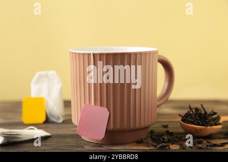 Weißer Keramikbecher mit Teebeutel-Etikett auf braunem Hintergrund. Draufsicht Stockfoto