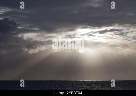 Sonnenlicht, das durch Wolken strahlt, erzeugt Krepuskulare Strahlen, die auf dem Indischen Ozean auf Reunion Island reflektieren. Stockfoto