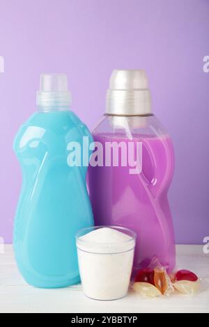 Waschmittel mit Waschpulver und Kapseln auf violettem Hintergrund. Draufsicht Stockfoto