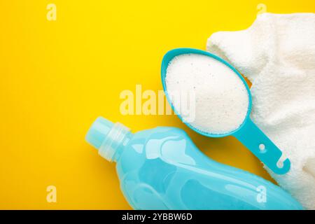 Waschmittel mit Waschpulver und Handtuch auf gelbem Hintergrund. Draufsicht Stockfoto