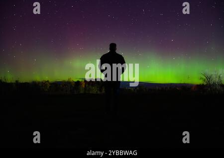 Silhouette eines Mannes, der Nordlichter am Nachthimmel in Kanada beobachtet. Stockfoto