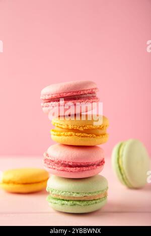 Ein vertikaler Stapel von drei Makaronen auf rosa Hintergrund. Süßes Dessert. Draufsicht Stockfoto