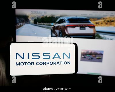 Person mit Smartphone und Logo der japanischen Firma Nissan Motor Corporation auf dem Bildschirm vor der Website. Schwerpunkt auf dem Display des Telefons. Stockfoto