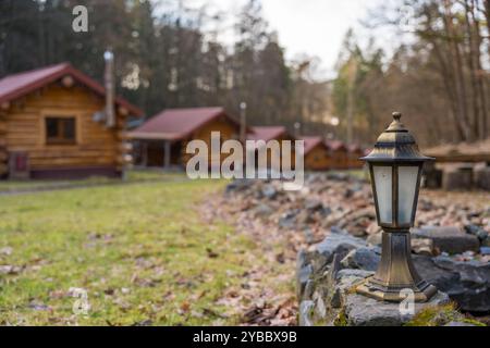Kleine Holzhäuser in einem Wald an einem bewölkten Wintertag. Vintage Straßenlaterne im Vordergrund Stockfoto