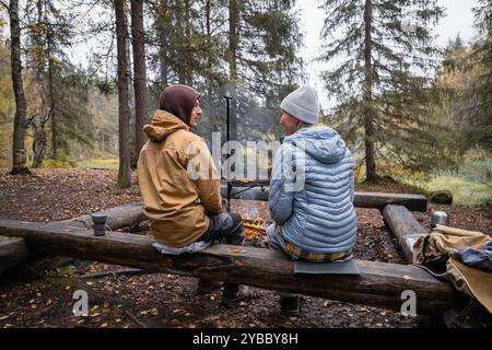 Mann und Frau kochen am Lagerfeuer im Wald Stockfoto