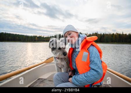 Eine Frau in einer Schwimmweste und ihr Hund sitzen in einem Boot Stockfoto