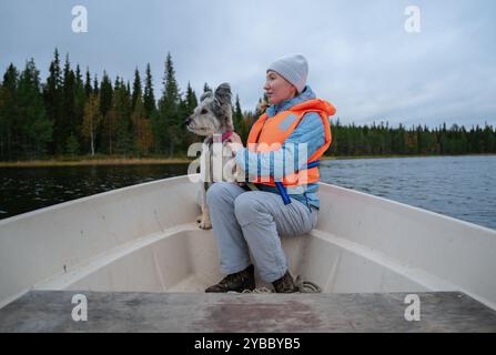 Eine Frau in einer Schwimmweste und ihr Hund sitzen in einem Boot Stockfoto