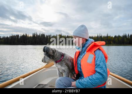 Eine Frau in einer Schwimmweste und ihr Hund sitzen in einem Boot Stockfoto