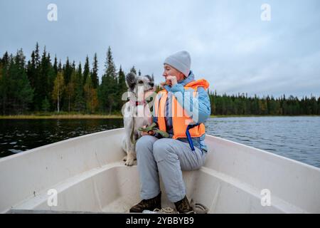 Eine Frau in einer Schwimmweste und ihr Hund sitzen in einem Boot Stockfoto