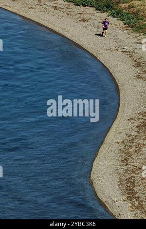 Gesunde Gewohnheiten: Mann, der am Sandstrand am Ohrid Lake läuft, Luftperspektive Stockfoto