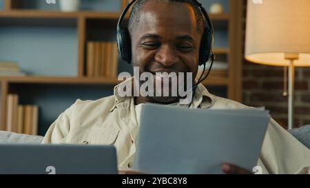 Afroamerikanischer Mann Geschäftsmann freiberuflicher Check Papierkram zu Hause lächelnder männlicher Unternehmer, der Dokumente liest, Finanzpapiere analysiert, eingegeben Stockfoto