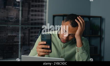 Frustriert gestresst verärgert besorgter afroamerikanischer Geschäftsmann männlicher Unternehmer Angestellter liest schlechte Nachrichten am Telefon im Büro Geschäftsproblem Stockfoto