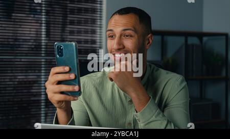 Lächelnder afroamerikanischer Mann spricht Video-Chat männlicher Geschäftsmann Freelancer Unternehmer Anruf Online-Konferenz mit Telefon sprechender Smartphone-Kamera Stockfoto