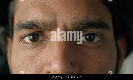 Extremer Makrobereich Nahansicht Teil männliches Gesicht braune Augen ernste unglückliche Ethnizität Mann Blick auf Kamera Sehstörungen Augenchirurgie Laser Vision Stockfoto
