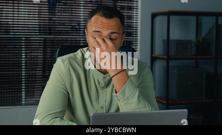 Müde gestresst erschöpft afroamerikanischer Mann Geschäftsmann Angestellter Manager, der spät nachts im Büro arbeitete, überarbeitete von der Laptop-Arbeit überwältigt Stockfoto
