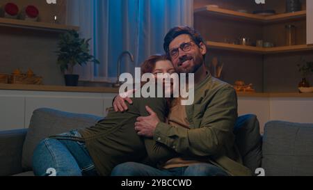 Liebevoller Mann schließt Laptop umarmt geliebte Frau auf der Couch zu Hause glückliches kaukasisches Ehepaar Ehemann umarmt Umarmung zusammen entspannend Stockfoto