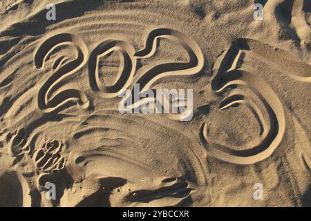 Die Inschrift ist die Zahl 2025 auf dem Sand am Strand des Flusses. Neujahrsweihnachten in warmen Ländern. Stockfoto