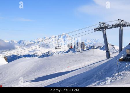 Atemberaubende Aussicht auf Sessellifte, die über schneebedeckte Berge in den drei Tälern hinaufsteigen. Skifahrer und Snowboarder im französischen Skigebiet Les Menuires. Stockfoto