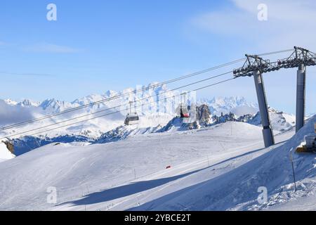 Atemberaubende Aussicht auf Sessellifte, die über schneebedeckte Berge in den drei Tälern hinaufsteigen. Skifahrer und Snowboarder im französischen Skigebiet Les Menuires. Stockfoto