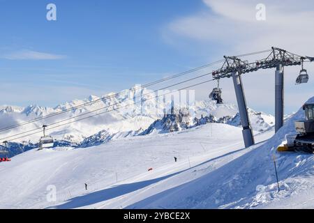 Atemberaubende Aussicht auf Sessellifte, die über schneebedeckte Berge in den drei Tälern hinaufsteigen. Skifahrer und Snowboarder im französischen Skigebiet Les Menuires. Stockfoto