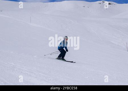Junge Skiläufer im Action-Skifahren in einem europäischen Skigebiet. Seitenansicht des Skifahrers, der im Winterresort Les Menuires, Frankreich, abfährt. Stockfoto
