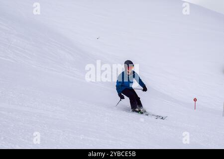 Junge Skiläufer im Action-Skifahren in einem europäischen Skigebiet. Seitenansicht des Skifahrers, der im Winterresort Les Menuires, Frankreich, abfährt. Stockfoto